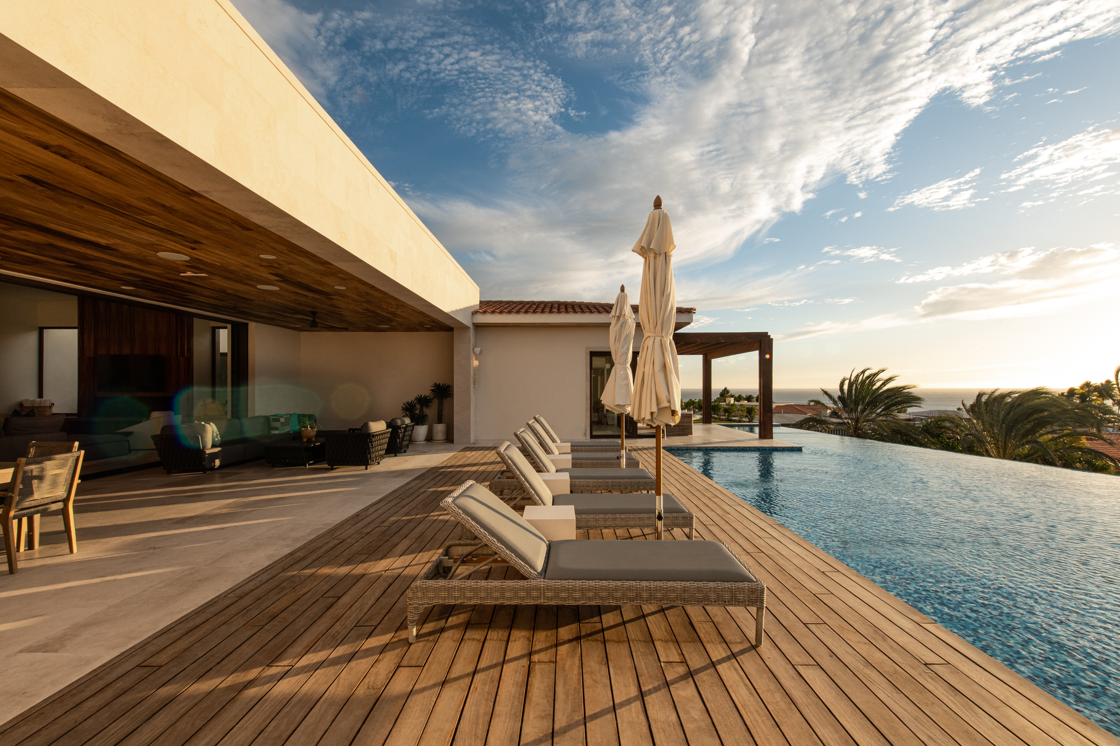 Villa deck with loungers and pool at sunset